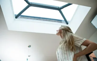 kobieta patrzy w okno dachowe